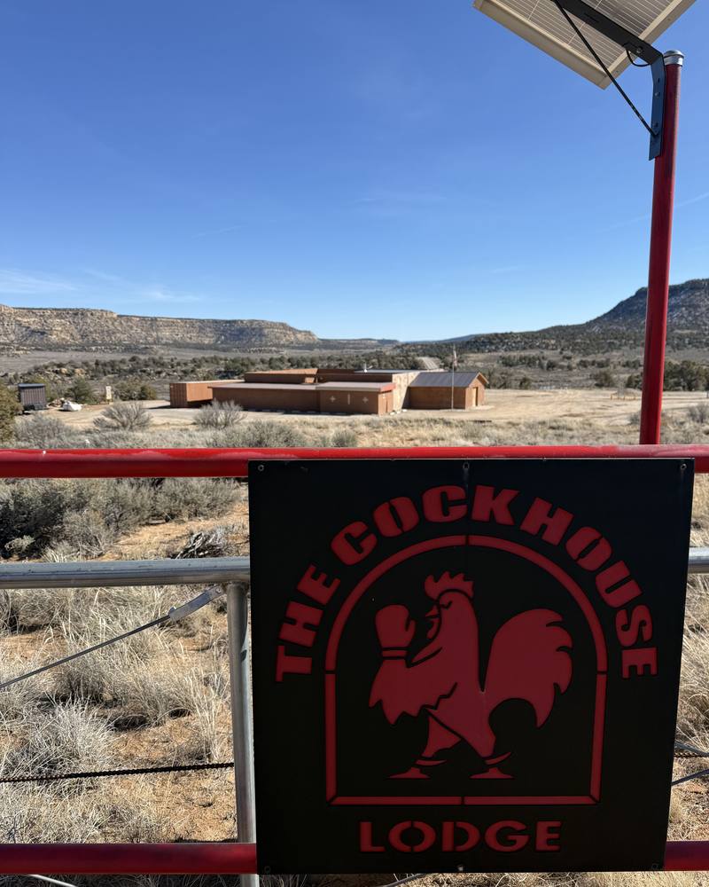 The Cockhouse Lodge gate sign with the lodge and mesa behind